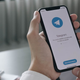 تمسك الأيدي بجهاز iPhone يعرض تطبيق Telegram